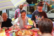 Basma und ihre Freundin Aurora servieren gemeinsam das Essen für die Nachbarschaft. Am Tisch kommen Menschen verschiedener Nationalitäten zusammen. Basma und ihre Freundin Aurora servieren gemeinsam das Essen für die Nachbarschaft. Am Tisch kommen Menschen verschiedener Nationalitäten zusammen.