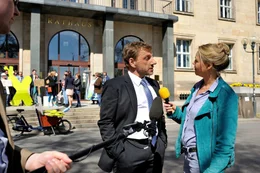 Gregor (Richy M&uuml;ller) gibt einer Journalistin (Astrid Kohrs) vor dem Rathaus ein Interview zum Ausbau des Dresdner Flughafens.