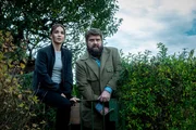 Behringer (Antoine Monot) und Ela (Cosima Henman) stehen vor der H&uuml;tte Gilbert.