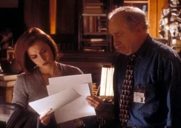 Der Anthropologe Arlinsky (Matthew Walker, r.) zeigt Scully (Gillian Anderson, l.) Fotos eines Au&szlig;erirdischen, der in einem Gletscher in Kanada gefunden wurde.