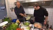 Frank Rosin (l.) gibt seinem neuesten Sch&uuml;tzling ein Kochcoaching und zeigt ihm, wie man richtig gute Mettburger und Cesar Salads macht ...