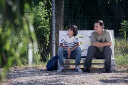 Dennis Placido (Tommaso Di Cola) und Professor Bernardini (Lino Musella) sitzen auf einer Bank.