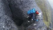 Eine Person steigt in eine Höhle hinab. Eine Person steigt in eine Höhle hinab.
