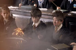 Hermione (Emma Watson) und Harry Potter (Daniel Radcliffe, M.) schauen schockiert, als der &uuml;berraschte Seamus Finnigan (Devon Murray) mit ansehen muss, wie sein Zauberstab w&auml;hrend eines Versuchs in Flammen aufgeht!