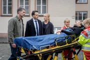 Jemand scheint es auf den Bekanntenkreis von Staatsanwalt Binz (Michael Rotschopf, 2.v.l.) abzusehen. Gemeinsam mit Dirk Trebbe (Simon Böer, l.) und Ina Zimmermann (Melanie Marschke, M.) beobachtet er, wie Kilian Cornelsen (Knut Berger, 2.v.r.) von Sanitäterinnen (Komparsinnen) weggefahren wird. Jemand scheint es auf den Bekanntenkreis von Staatsanwalt Binz (Michael Rotschopf, 2.v.l.) abzusehen. Gemeinsam mit Dirk Trebbe (Simon Böer, l.) und Ina Zimmermann (Melanie Marschke, M.) beobachtet er, wie Kilian Cornelsen (Knut Berger, 2.v.r.) von Sanitäterinnen (Komparsinnen) weggefahren wird.