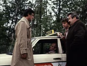 In einer Kiesgrube am Stadtrand wurde das Taxi des Taxifahrers Amann gefunden, der den fl&uuml;chtenden Scholz gefahren hat. Amann ist tot. Kriminalkommissar Lenz (Helmut Fischer, links), Kriminalobermeister Brettschneider (Willy Harlander, rechts) und Kriminalassistent Anton Faltenmayer (Henner Quest) wurden an den Tatort gerufen. In welchem Zusammenhang steht dieser Mord mit der Flucht des Theo Scholz?