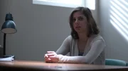 Vanessa sitting at a table being interrogated.