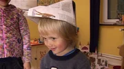 Ilvy bastelt einen Papierhut und schenkt ihn ihrem kleinen Bruder.