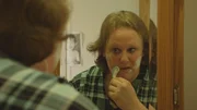 Leslie shaves in the mirror.