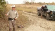 Warden Richards gestures to a group of hunters, Warden Fried stands at the wardens' truck.