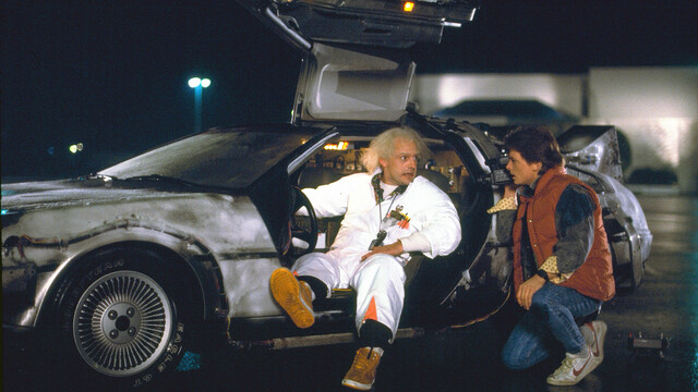 Mit Hilfe von Dr. Brown (Christopher Lloyd, l.) und dessen als Sportwagen verkleideter Zeitmaschine reist Vorstadtteenager Marty McFly (Michael J. Fox, r.) in die 1950er Jahre.