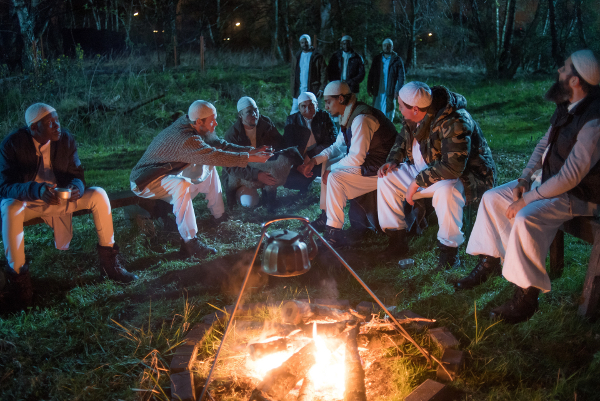 Imam Abu Nour (Lennart Lemster, l.) mit Melih (Yasin Boynuince, Mitte, r.) , Tobi (Rouven Israel, 2. v. r.) und anderen Männern beim Tee nachts am Lagerfeuer.