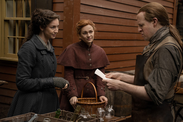 Claire (Caitriona Balfe) und Brianna (Sophie Skelton) geben bei einem Glasbläser das Gehäuse für eine Spritze in Auftrag.