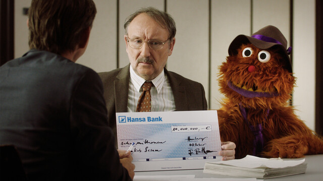 Jakob Sesam (Rainer Bock) und Nepomuk bekommen einen Scheck über zehn Millionen für ihren Film.